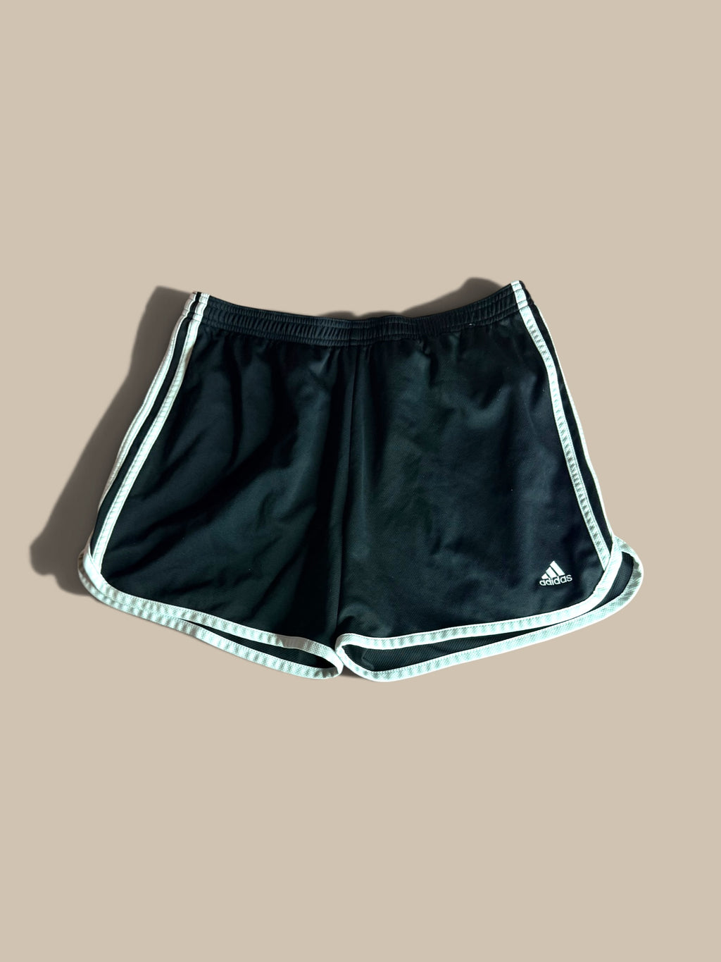 adidas Marathon 20 black running shorts with white 3-Stripes, displayed flat against a solid beige background.