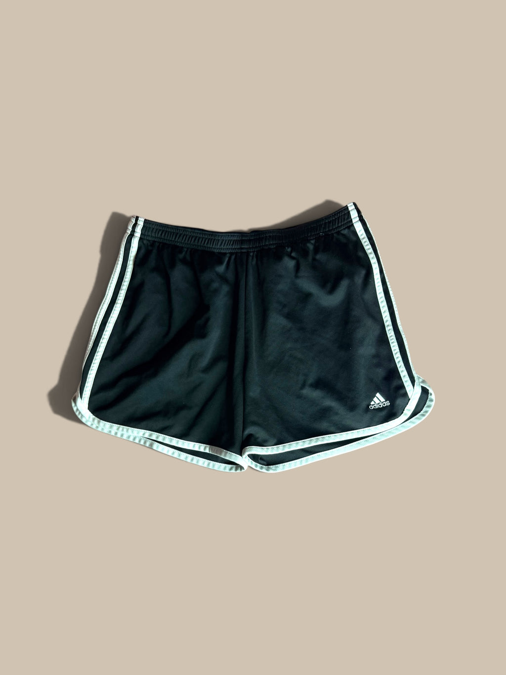 adidas Marathon 20 black running shorts with white 3-Stripes and a white logo on the lower right leg, displayed flat against a solid beige background.