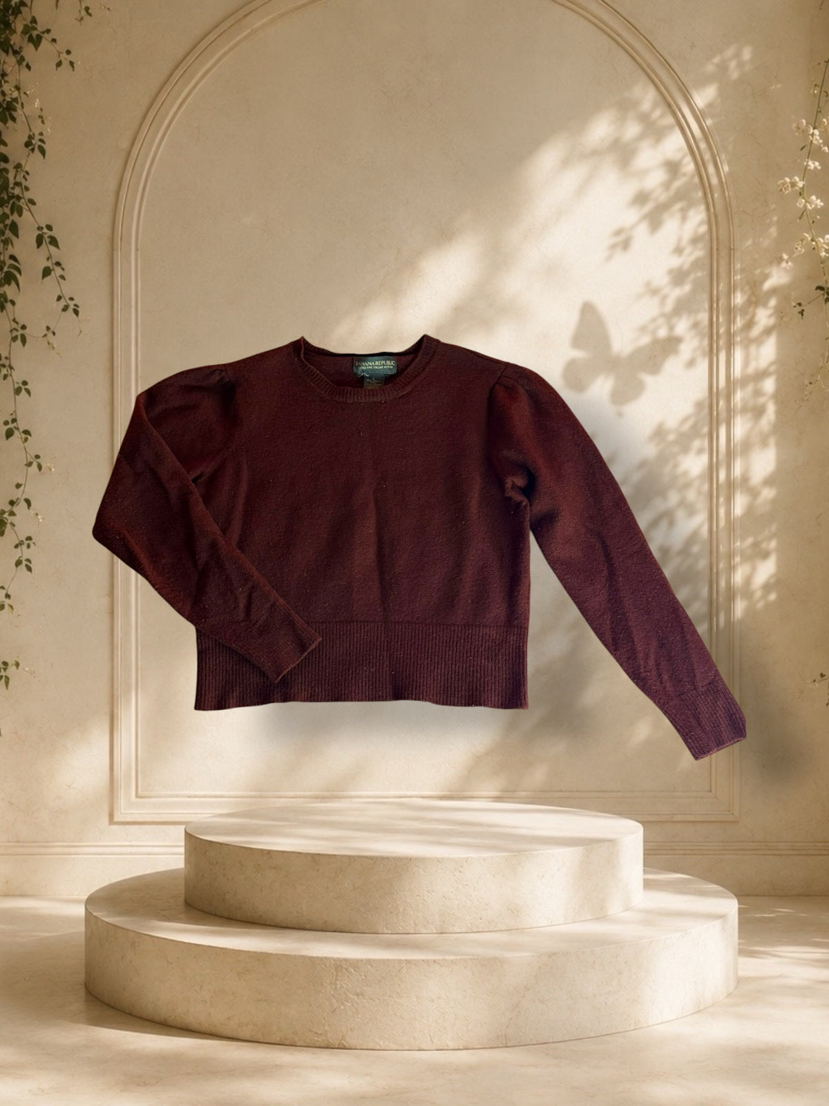 A Banana Republic Extra Fine Italian Merino sweater sits atop a pedestal with golden hour lighting.