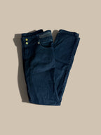 Dark blue B.B. Jeans rhinestone waistband skinny jeans folded neatly on a solid beige background, featuring a silver chain detail at the waistband and gold-tone metal buttons.