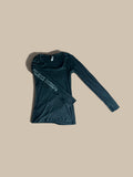 Bella Pilates Design charcoal gray long-sleeve tee with graphic lettering “Pilates Design” on right sleeve, laid flat on a solid beige background.