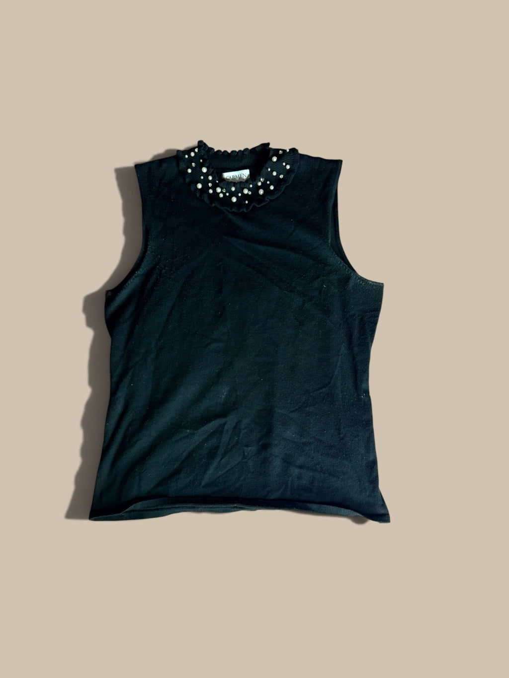 Carmen Marc Valvo black faux-pearl and rhinestone embellished knit shell, laid flat on a solid beige background.