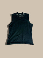A Carmen Marc Valvo black embellished ruffle mock-neck knit shell with small white pearls, laid flat on a solid beige background.