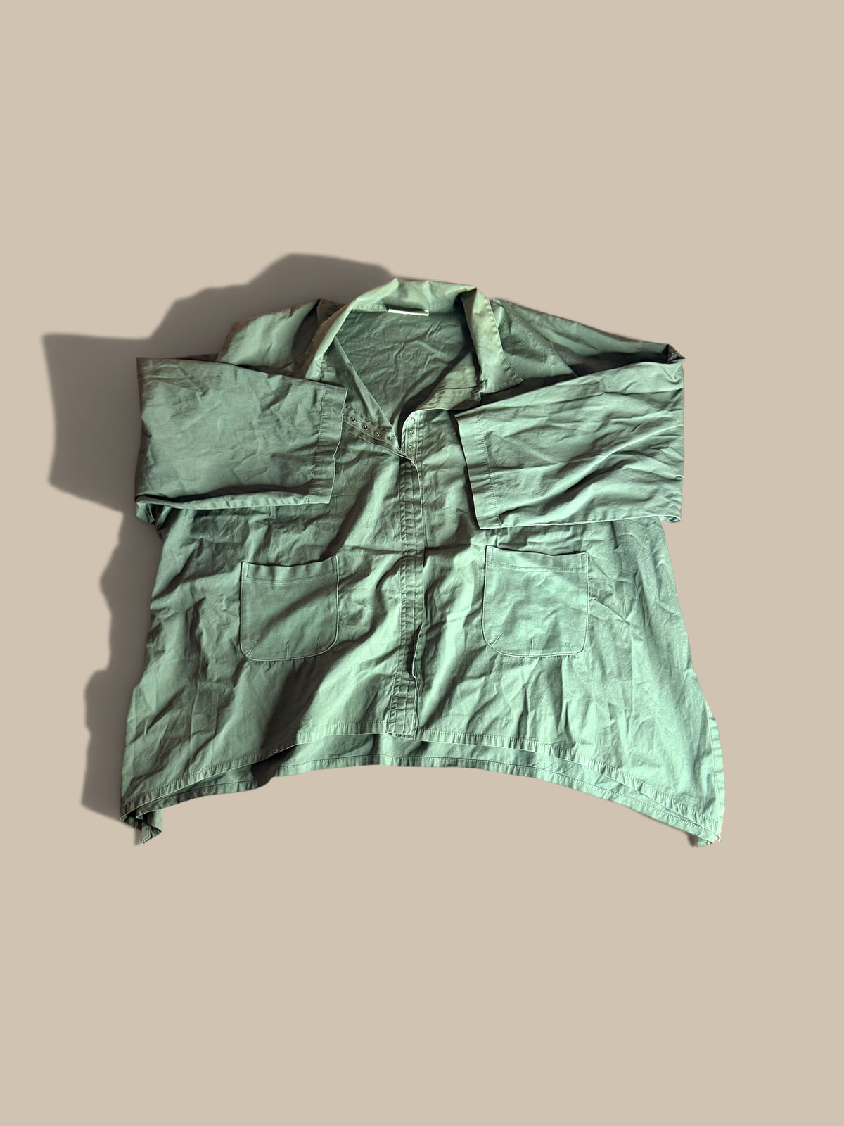 Eleven Stitch Design sage green asymmetrical snap-front pocket shacket front flat lay with sleeves folded