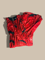 A Enfocus Petite crimson red and black abstract floral chiffon maxi dress shown folded in half, laid flat on a beige background.