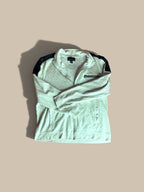An I.N.C. International Concepts light gray heather full-zip knit jacket with black shoulder panels, folded and displayed on a solid beige background with a soft shadow.
