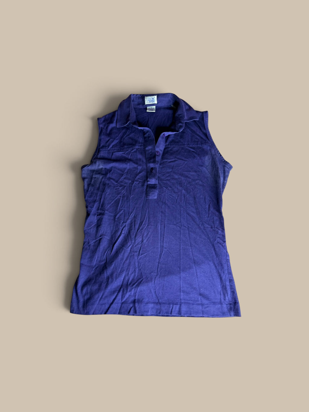 A sleeveless, Leon Levin deep purple indigo polo shirt shown in a second front flat lay.