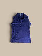 A sleeveless, Leon Levin deep purple indigo polo shirt, laid flat against a solid beige background.