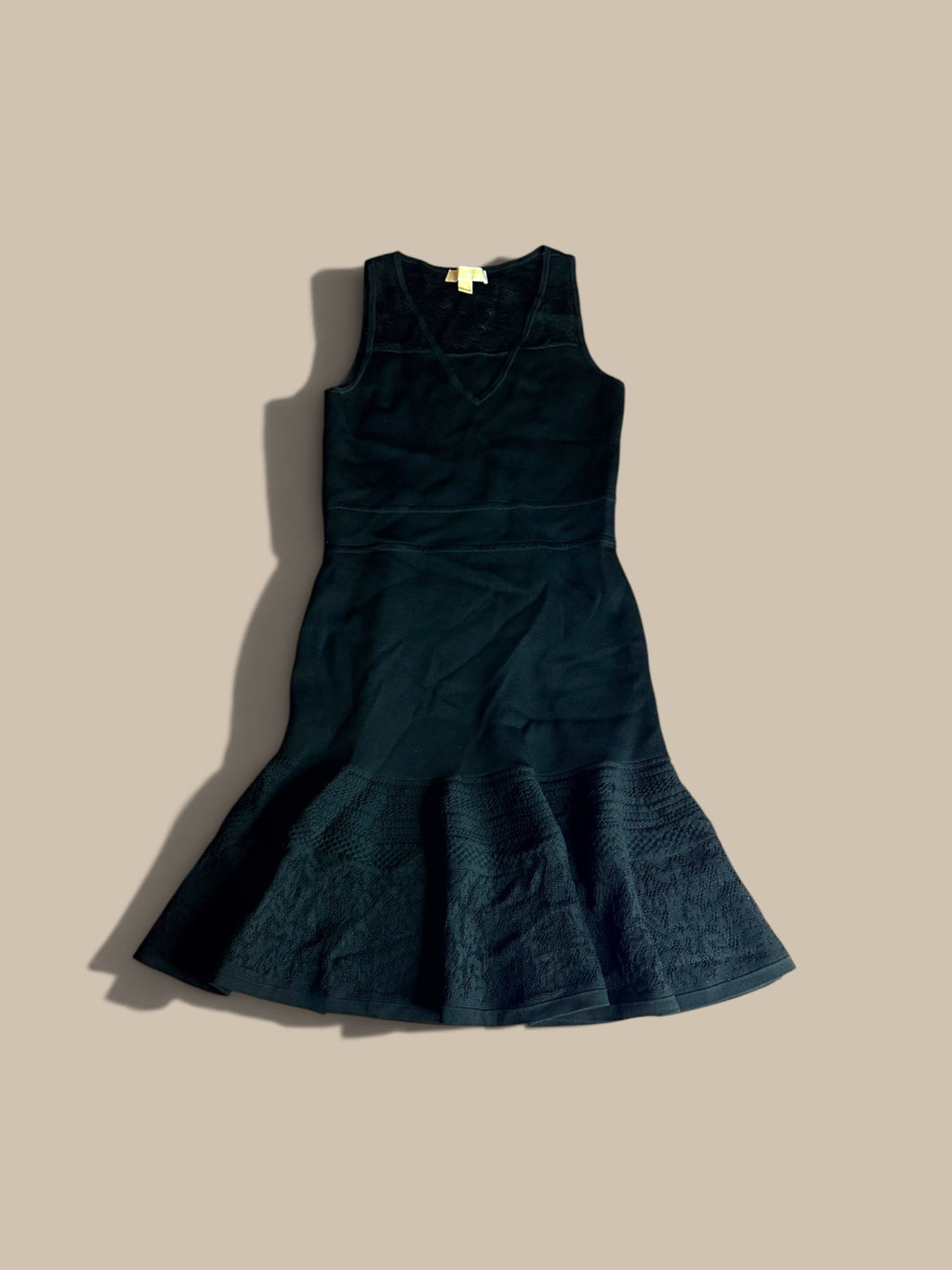 A MICHAEL Michael Kors black sleeveless pointelle knit dress front product view, laid flat on a solid beige background.