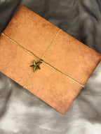 Vintage-style brown envelope wrapped with crisscrossed decorative rope and finished with a star charm, an example of Nessa Samantha handwritten snail mail packaging.