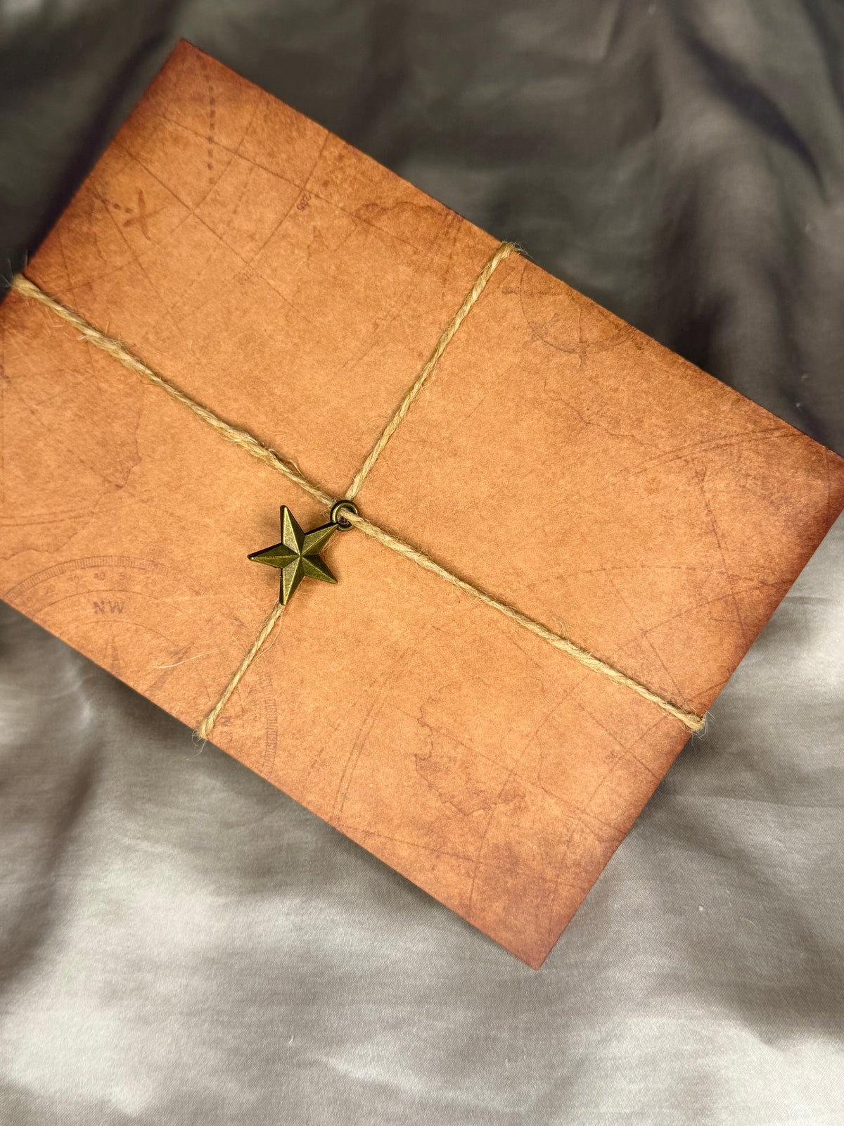 Vintage-style brown envelope wrapped with crisscrossed decorative rope and finished with a star charm, an example of Nessa Samantha handwritten snail mail packaging.