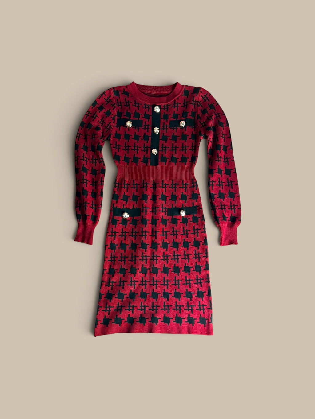 A Nessa Samantha houndstooth knit sheath long-sleeve knit dress featuring a red and black star-patterned houndstooth design, with a buttoned neckline and decorative buttons on the chest pockets, shown against a solid beige background.