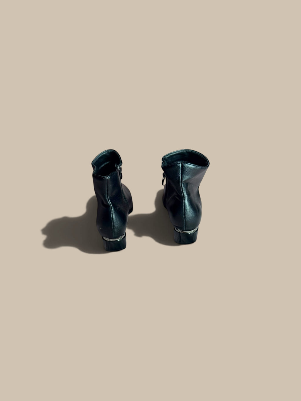 Nessa Samantha black ankle boots standing upright showing back view against a beige background.